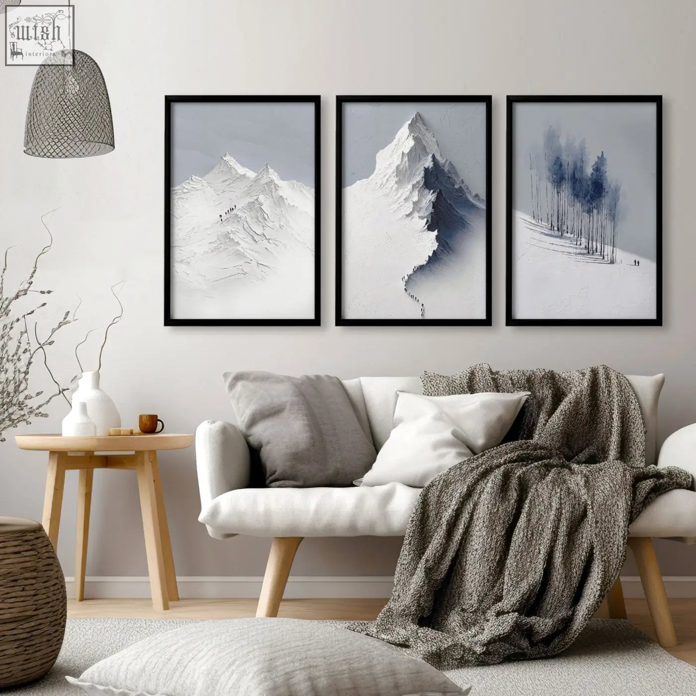 Three framed black and white mountain landscape wall art prints in grey white and blue hang above a sofa in a living room