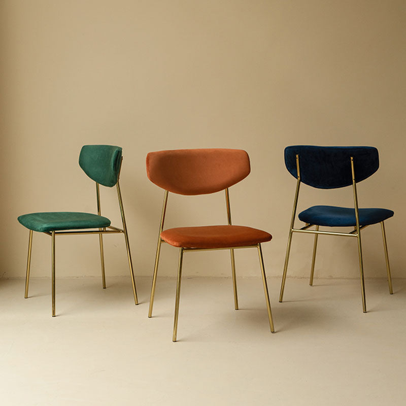 Three velvet urban dining chairs in green orange and navy with sleek gold metal frames for stylish dining seating