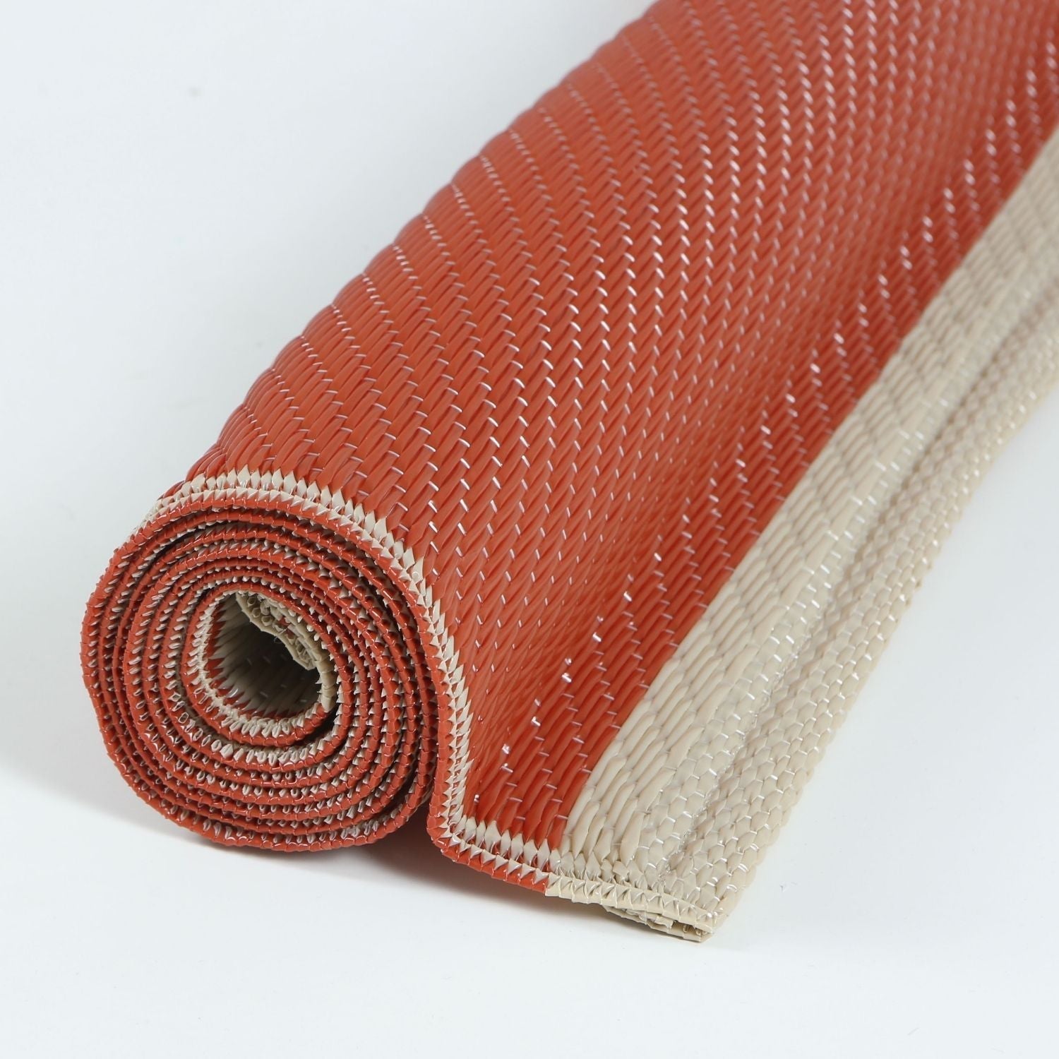 A rolled-up urban outdoor rug in terra and beige with a woven diagonal pattern perfect for outdoor use