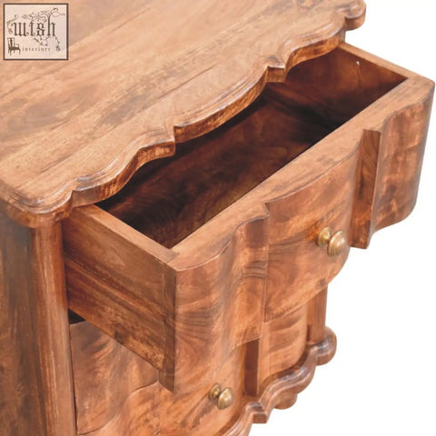 Valencia bedside table in solid mango wood with warm tones scalloped top and curved drawer fronts with brass knobs