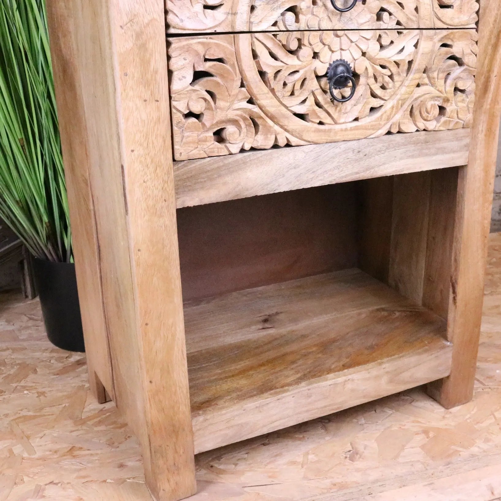 Vansura carved bedside table made of light wood with intricate floral patterns and black metal ring pulls bedside table