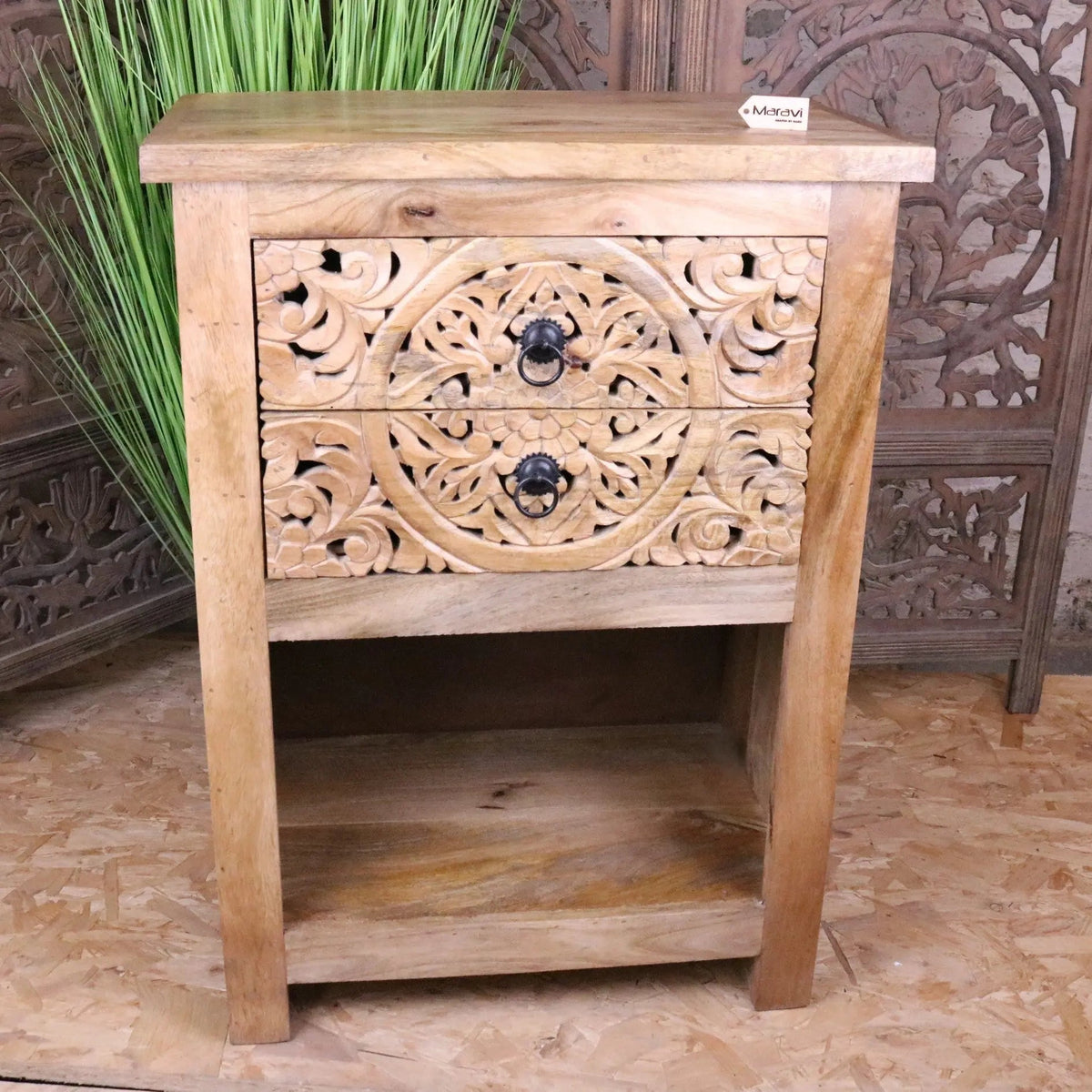 A light wood vansura carved bedside table with two intricately carved drawers and black metal ring pulls bedside table