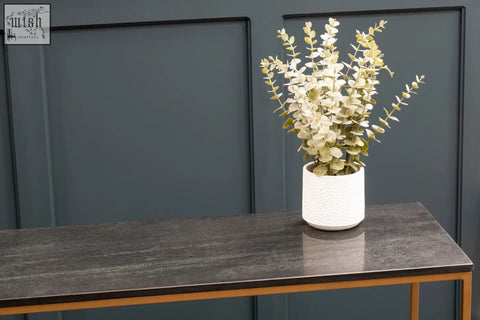 White textured ceramic vase with artificial eucalyptus on varana black marble console table with gold iron frame