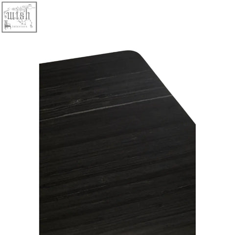Corner of varana black marble dining table showing smooth black wooden edge with dark finish and visible grain texture