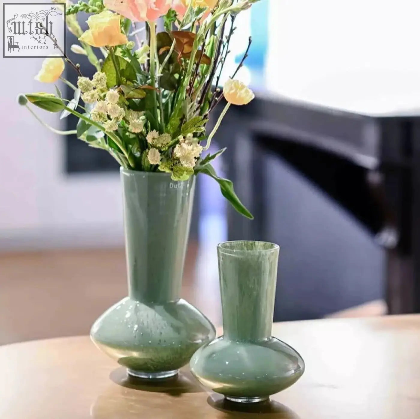 A sleek sage green ceramic vase in the dutz collection with a flared neck and rounded base from mouth blown glass series