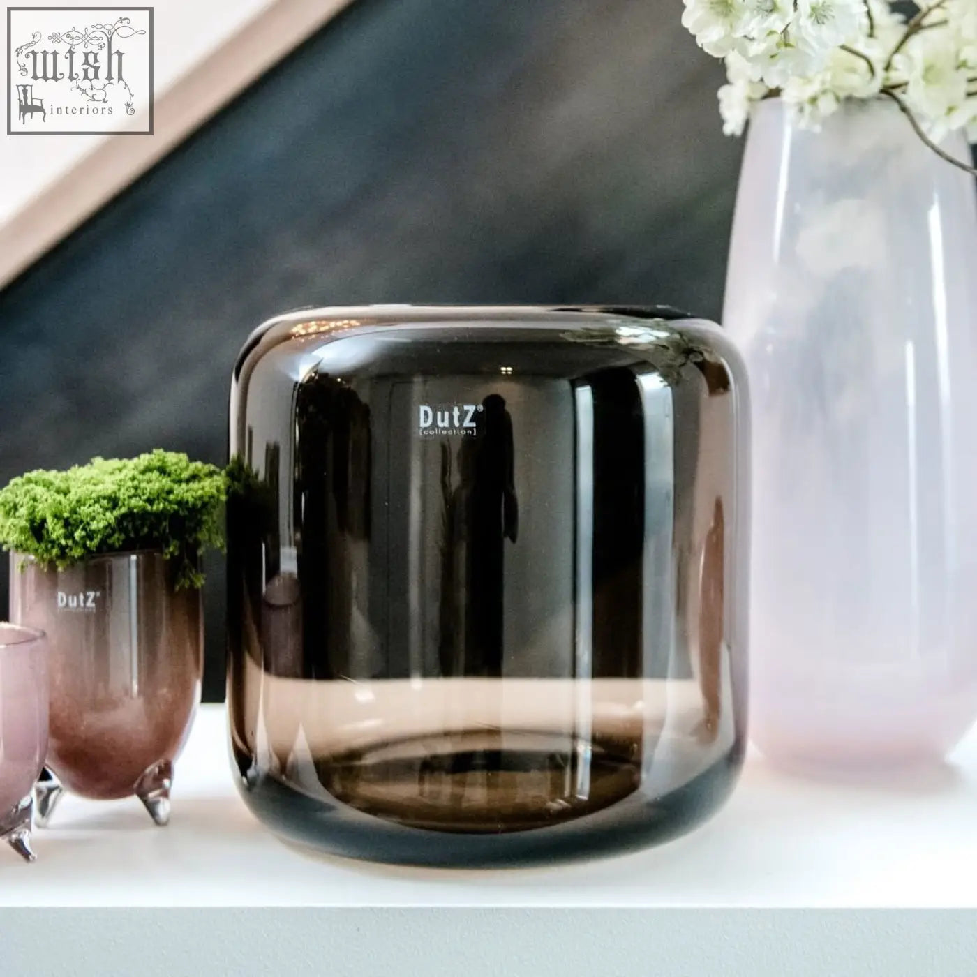 A sleek mouth blown glass vase in smoky brown from the dutz collection with the dutz logo etched on the side