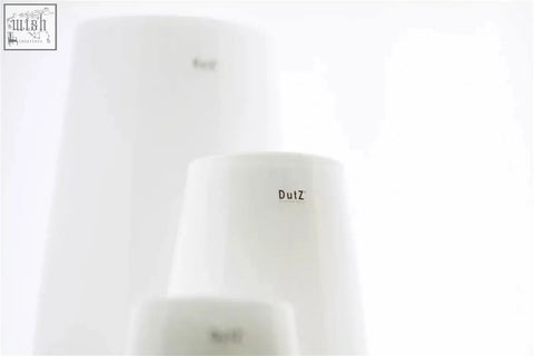 White cylindrical air purifiers from dutz collection featuring mouth blown glass with minimalist design and logo