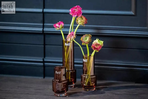 Set of three amber mouth blown rona vases from dutz collection holding vibrant pink and green flowers