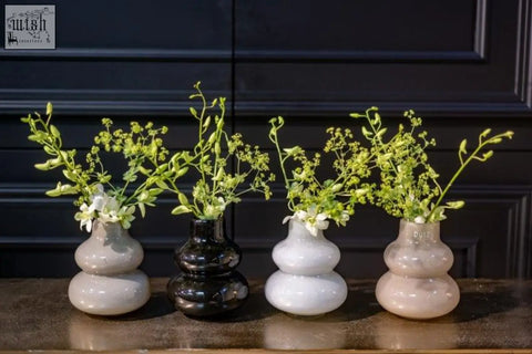 Four gourd-shaped matte gray, glossy black, and pastel mouth blown vases from dutz collection holding greenery in smoke finish