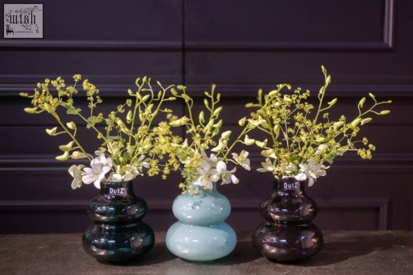 Three stacked-globed mouth blown glass vases in teal light blue and dark green from dutz collection holding white flowers