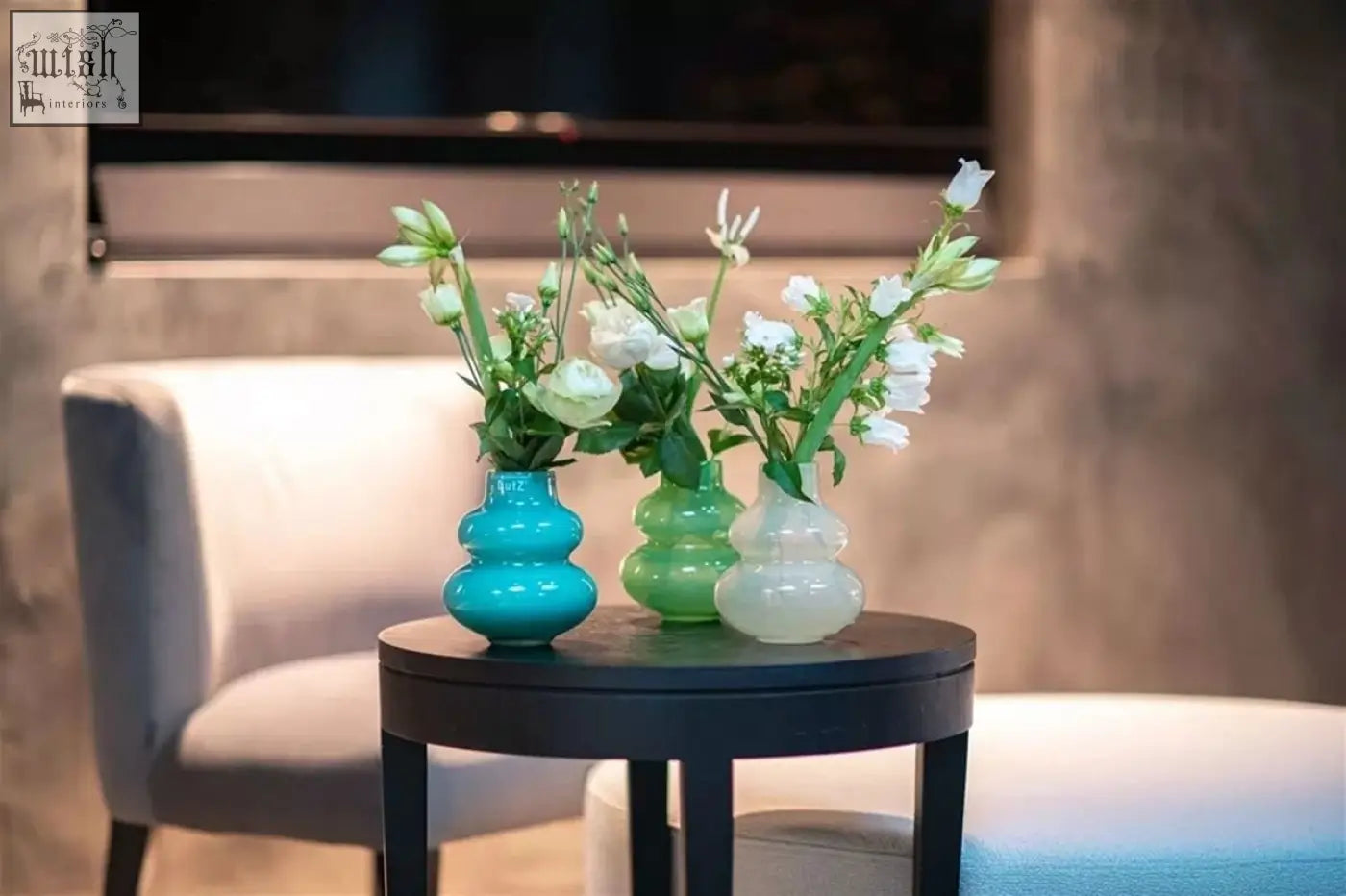 Three stacked mouth blown glass vases from dutz collection in turquoise green and frosted white holding white flowers