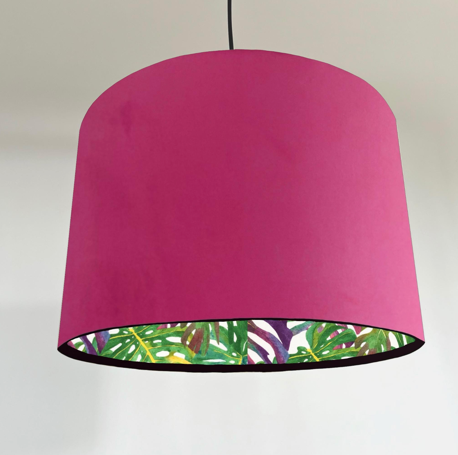 A vibrant fuchsia velvet double sided drum lampshade with tropical leaf lining for a handmade ceiling light shade