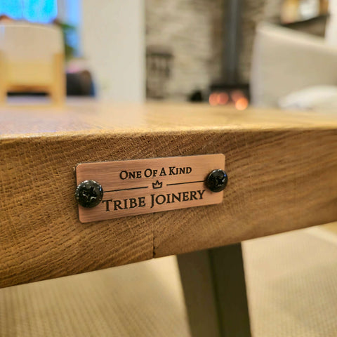 A bronze plaque with tribal joinery engraving on the back of the vena live waney edge coffee table edge coffee table