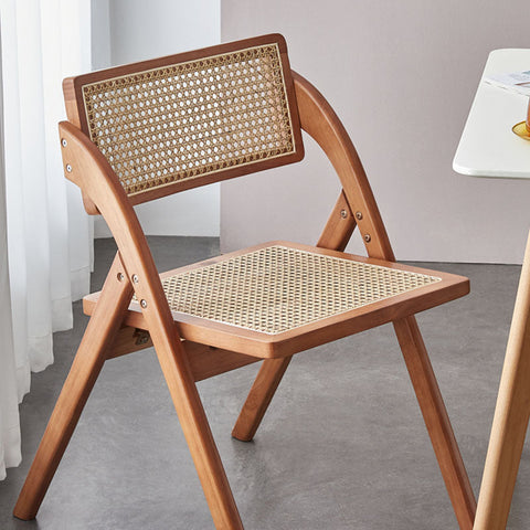 A light brown rubber wood vera foldable rattan dining chair with woven cane back and seat perfect for small spaces