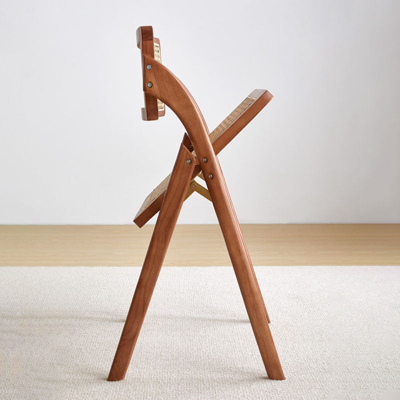 A sleek light brown rubber wood vera foldable rattan dining chair with woven cane seat and backrest