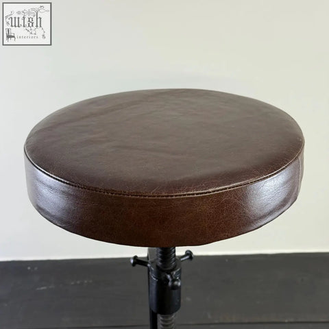 Brown leatherette circular bar stool with cast iron black adjustable height base for industrial use