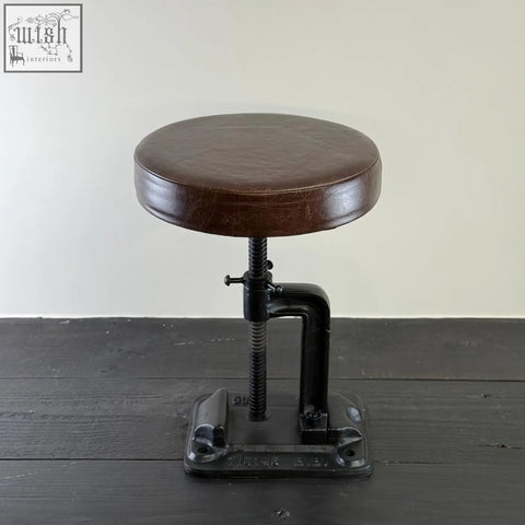 Brown leatherette round bar stool with cast iron black base and adjustable height for industrial style seating