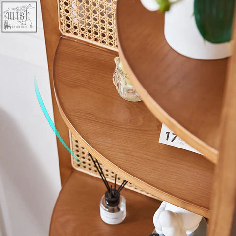 Curved ash wood vicente triangle bookshelf with woven rattan backing displaying glass diffuser and white ceramic vase