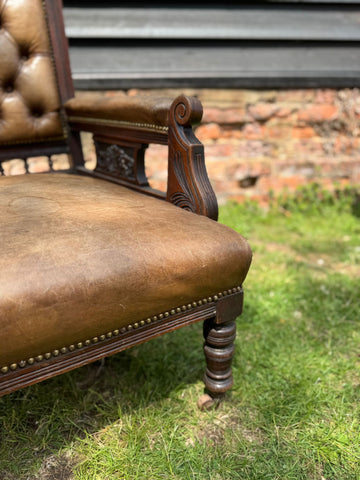 Victorian carved walnut library chair in antique brown leather with brass nailhead trim and button back design