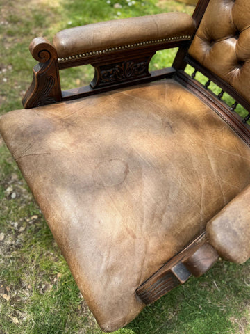 Antique brown leather tufted office chair with carved walnut wooden frame perfect for a victorian library setting