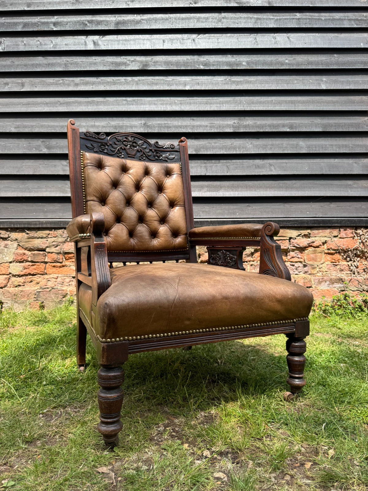 Victorian carved walnut library chair with antique brown leather tufted button back and ornate wood frame