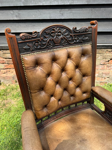 Victorian carved walnut library chair with brown leather tufted button back and ornate floral wood frame