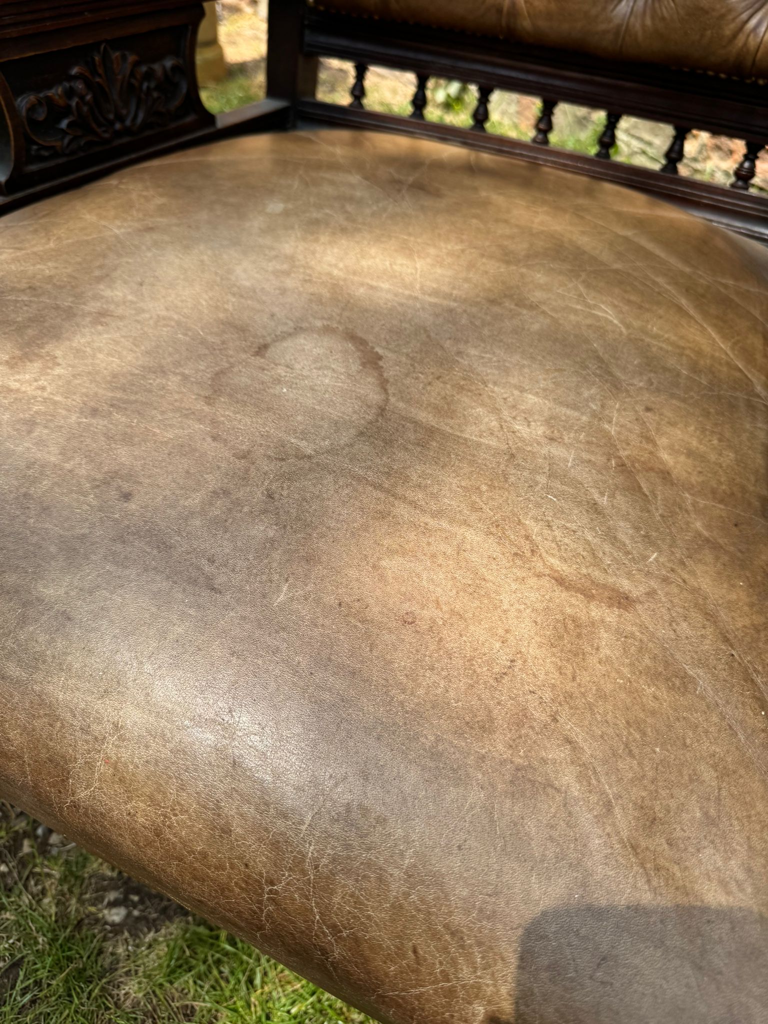 Brown leather seat with visible wear on a Victorian carved walnut library chair button back fireside armchair