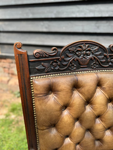 Victorian carved walnut library chair with tufted leather seat and ornate floral dark wood frame for fireside use