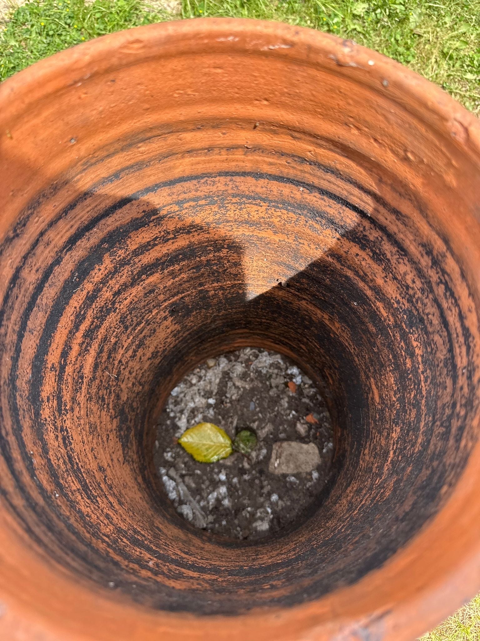 A victorian terracotta chimney pot garden planter with rough reddish-brown interior and visible concentric rings