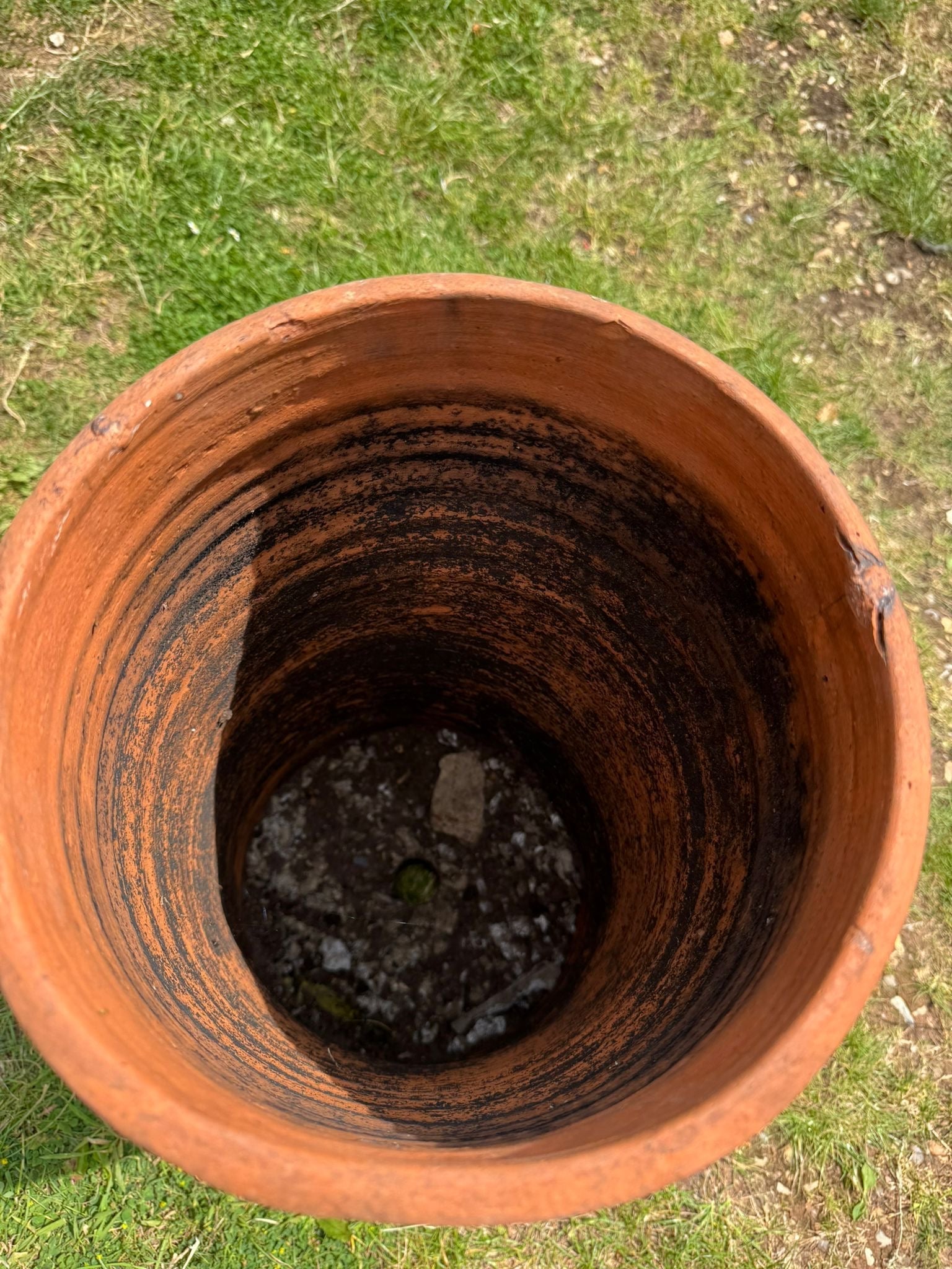 Victorian terracotta chimney pot with rough earthy orange exterior and darkened interior streaks as garden planter