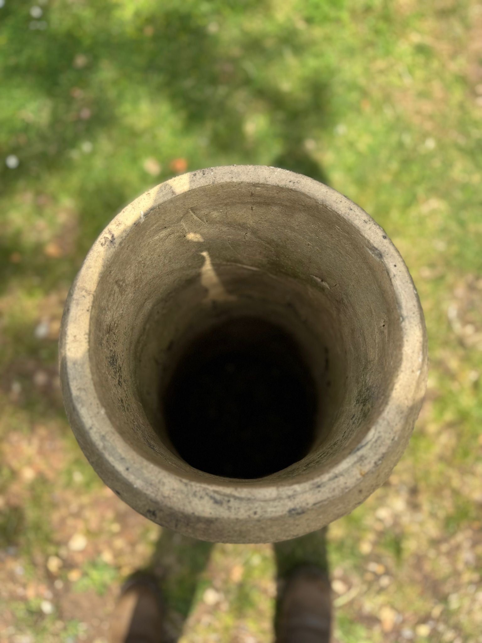 Weathered cylindrical concrete chimney showing rough texture in a victorian yellow terracotta rolled rim chimney pot planter