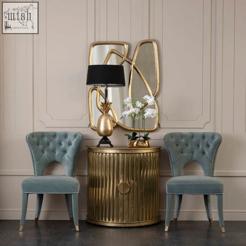Gold pineapple table lamp with black shade next to blue velvet tufted dining chair for stylish dining decor