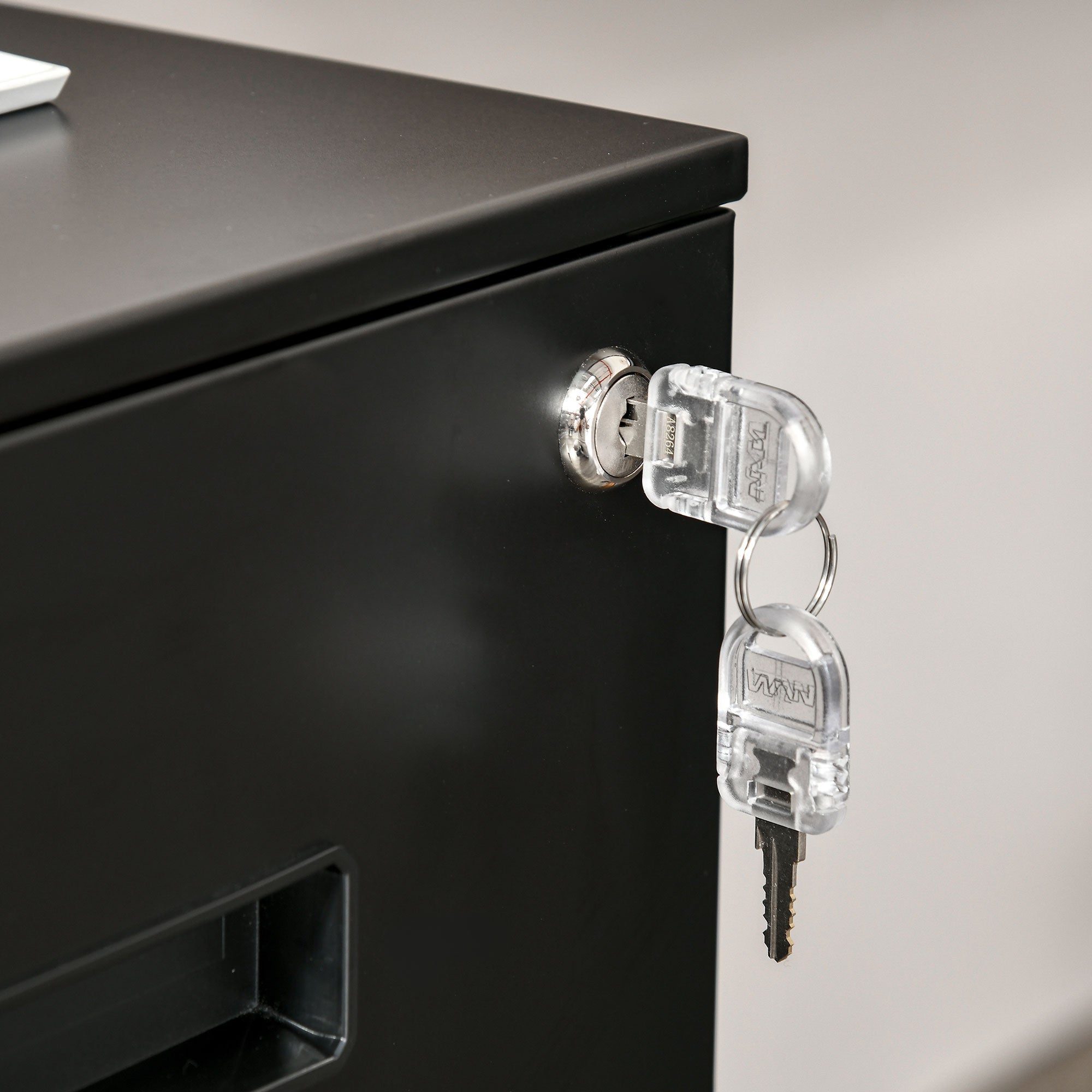 Clear keys inserted into the lock of a black vinsetto metal filing cabinet with narrow design for home office use