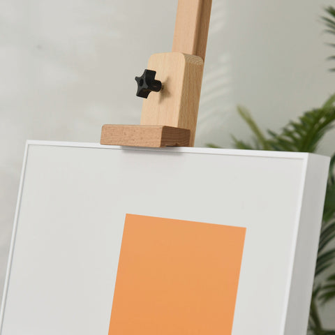 Light wood beech wood easel with black star knob holding white canvas with orange square on nature wood finish