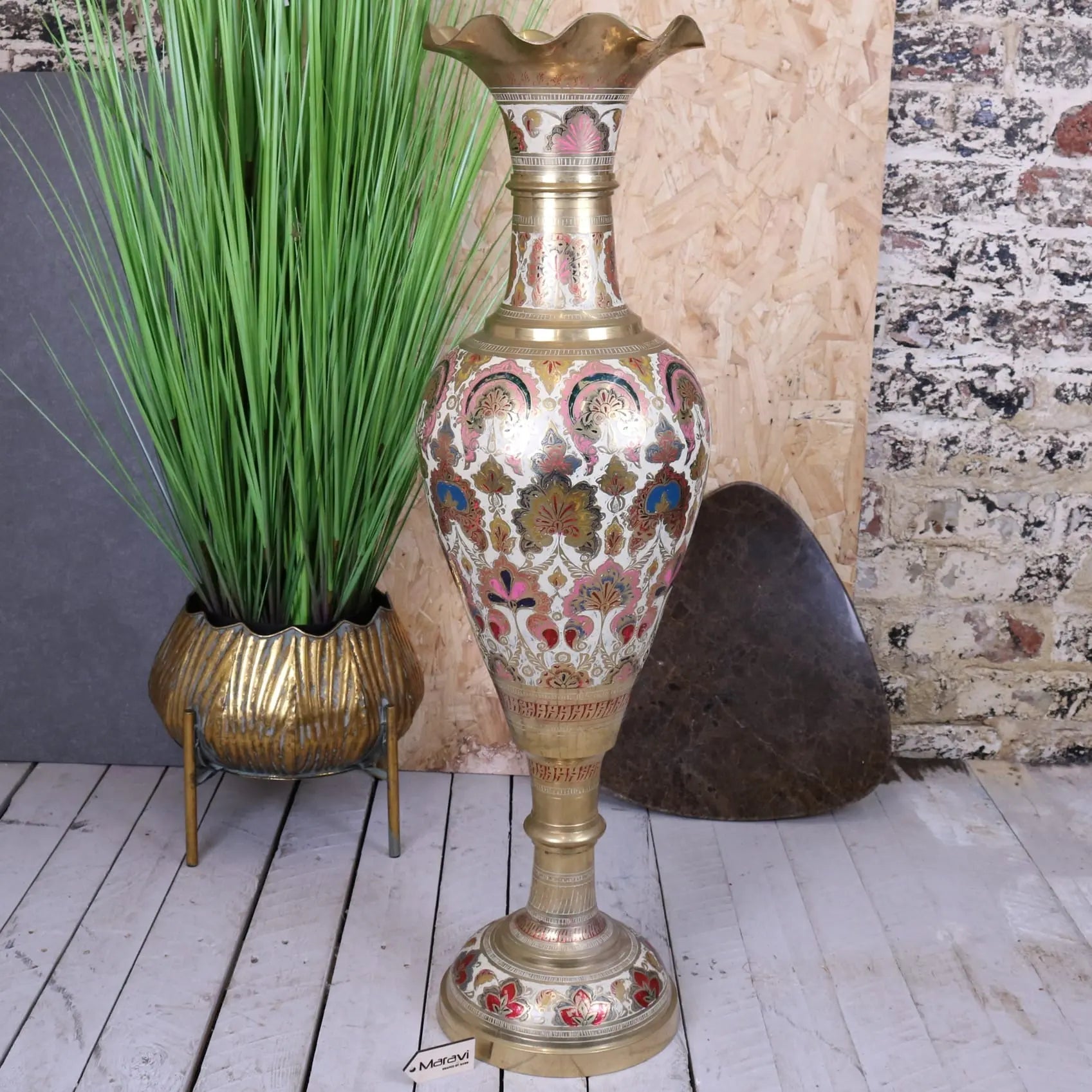 A tall vintage brass vase with pink blue gold enamel floral patterns and a large scalloped edge design