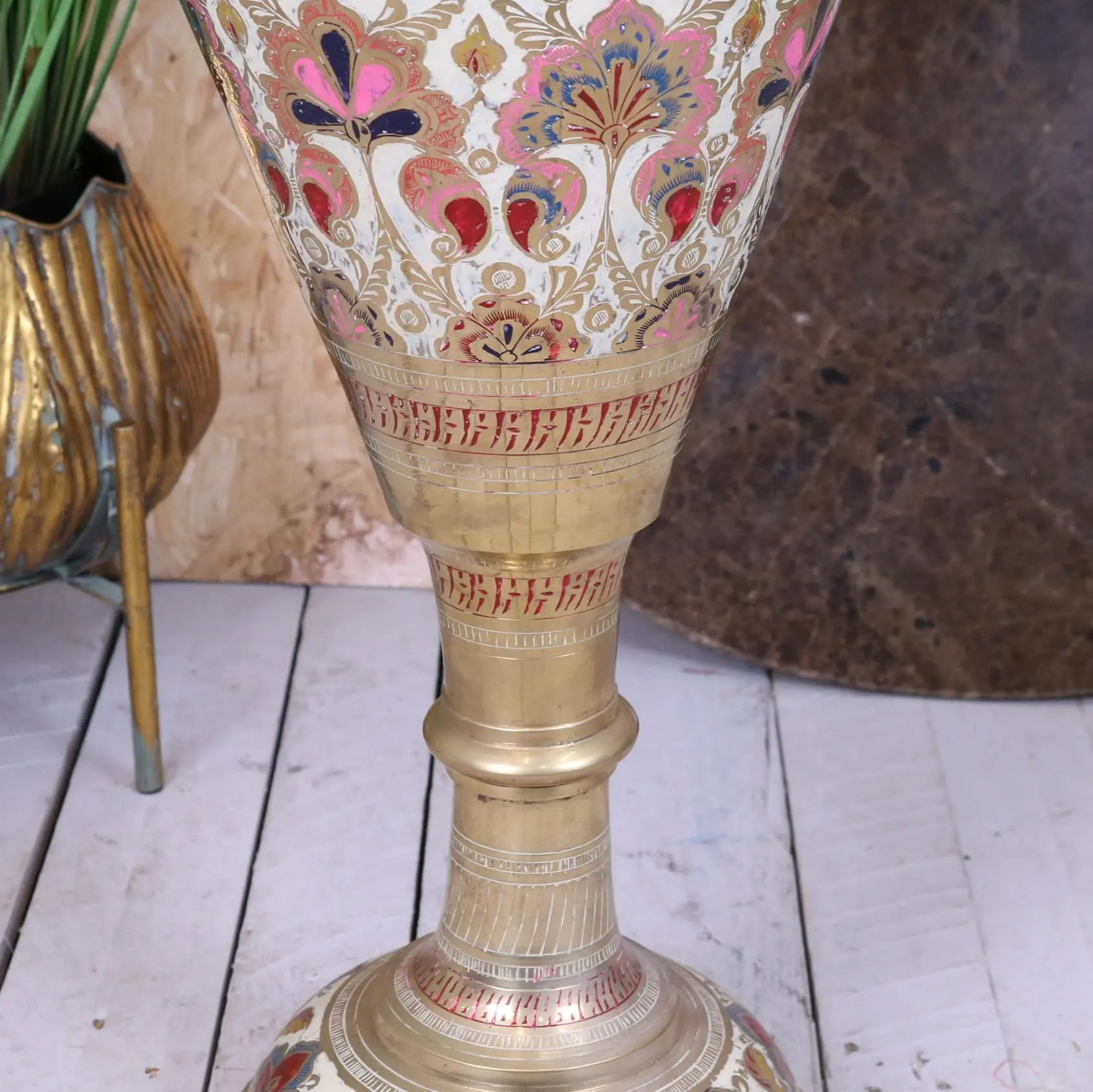 A tall vintage brass vase with scalloped edge and intricate pink red gold floral patterns on white background