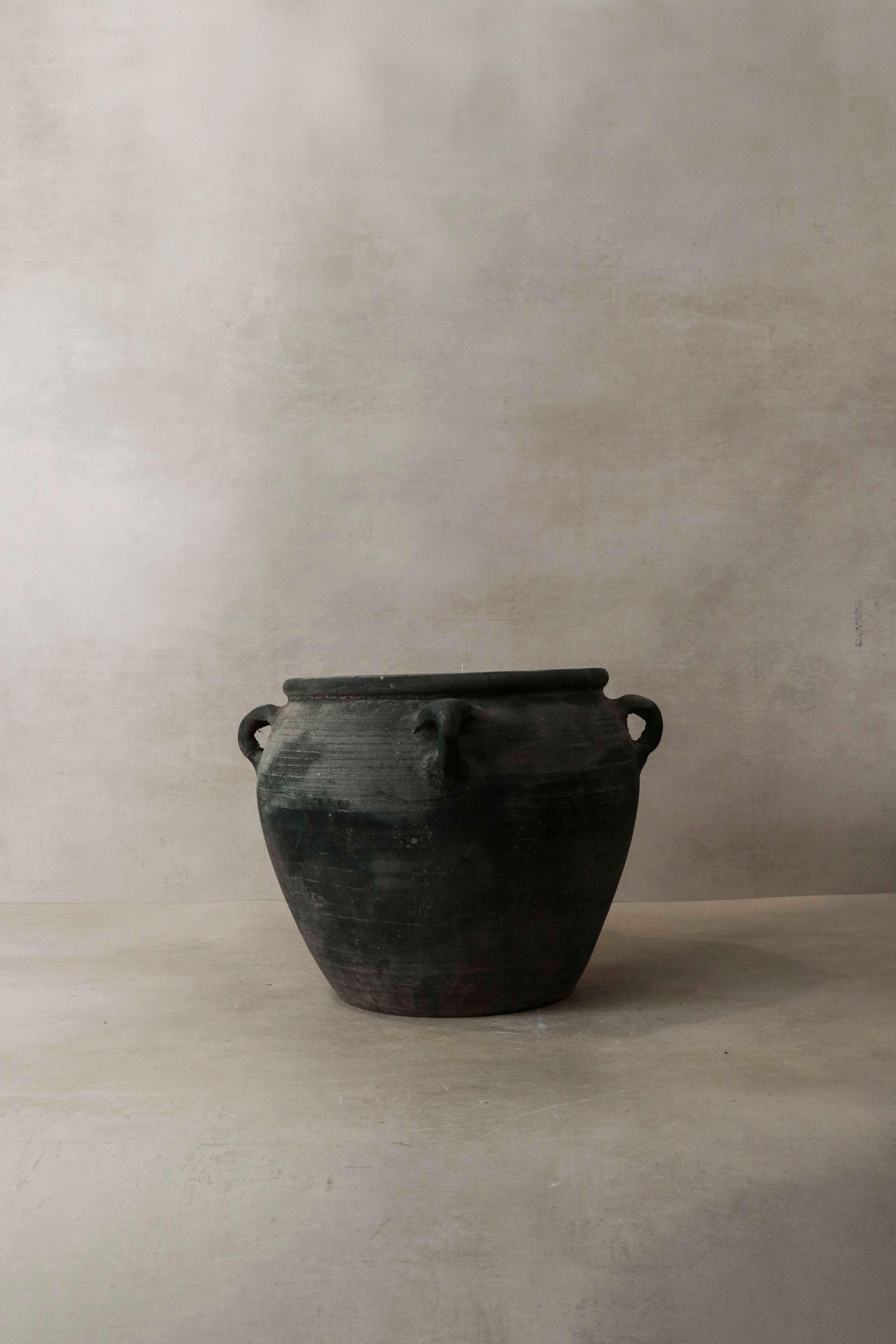 Vintage dark rustic ceramic jar with two looped handles on either side perfect for decor or storage
