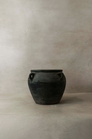 Vintage dark pot with ears made of dark matte ceramic featuring two small looped handles on either side