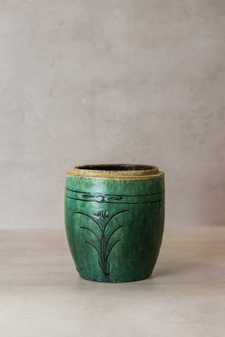 Vintage emerald green pot with a rustic ceramic finish, subtle glaze, hand-painted black floral motifs, and worn rim