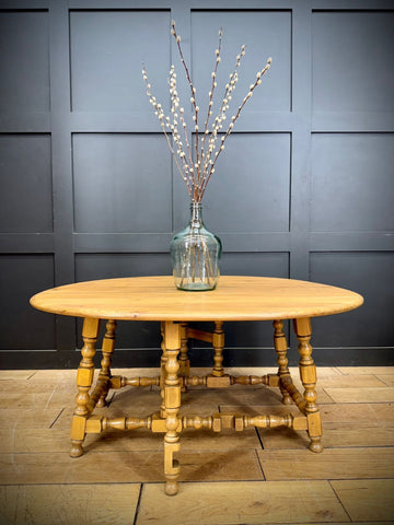 Light-colored wooden oval vintage ercol model 506 drop-leaf coffee table with turned legs in light elm tall windsor style