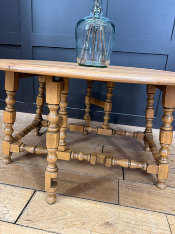 A vintage ercol model 506 drop-leaf coffee table in light elm with rustic oak turned legs and a sturdy ornate base