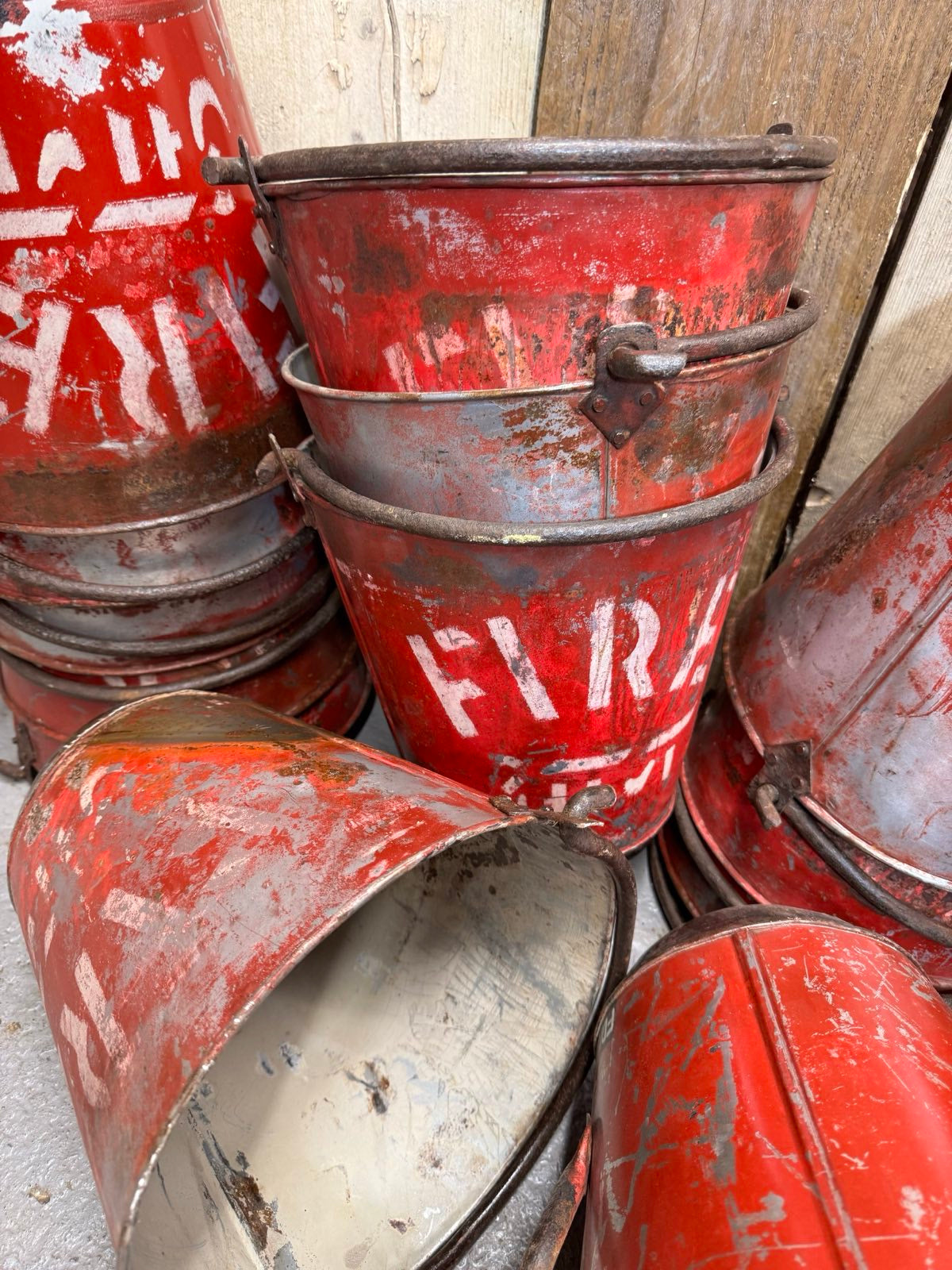 Vintage galvanised hanging fire buckets in rusty red with faded white lettering and weathered handles for plants or decor
