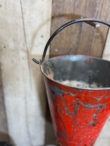 Vintage galvanised hanging fire bucket in weathered red metal with black handle for use as a planter or hanging basket