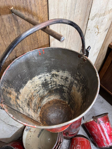 Vintage red enamel fire bucket with black metal handle chipped paint used as hanging planter or basket