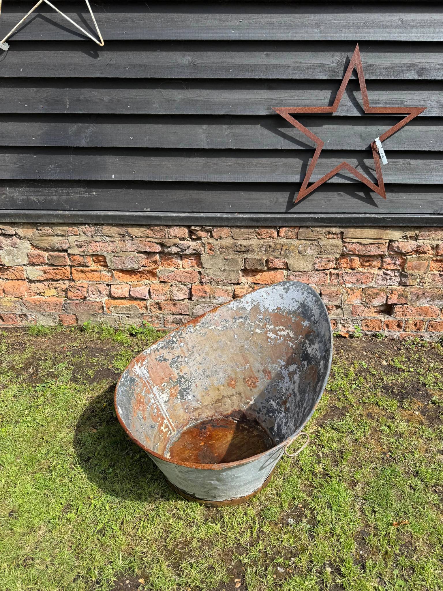 Weathered oval-shaped vintage galvanised metal bath with rust patches and peeling paint for garden display