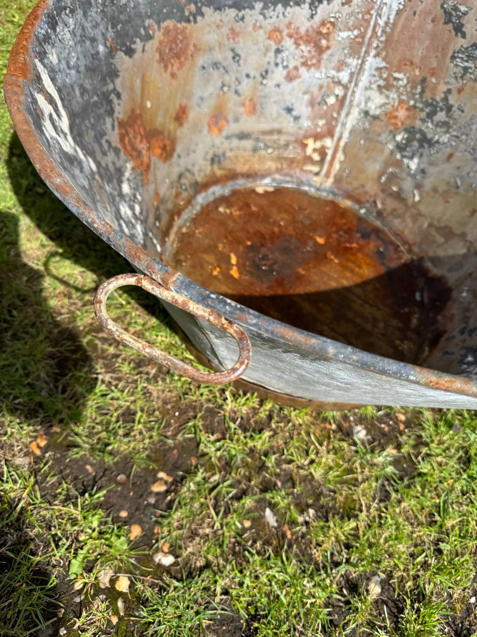 Rusty galvanised metal bath bucket with reddish-brown patina and loop handle for vintage garden display