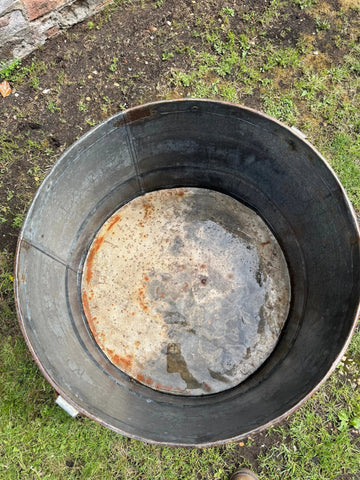 Weathered black galvanised metal round garden planter tub with rust stains and rustic outdoor pot design