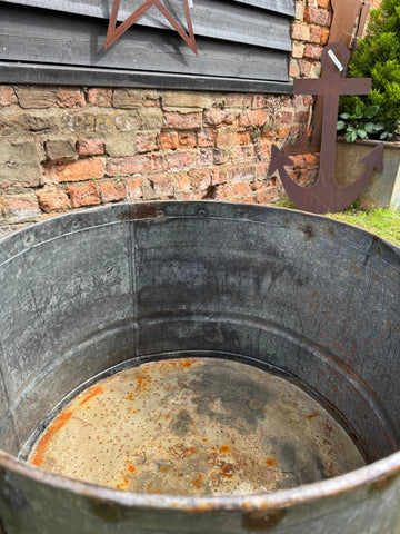 Rust-stained vintage galvanised metal round garden planter tub with a weathered rustic outdoor look