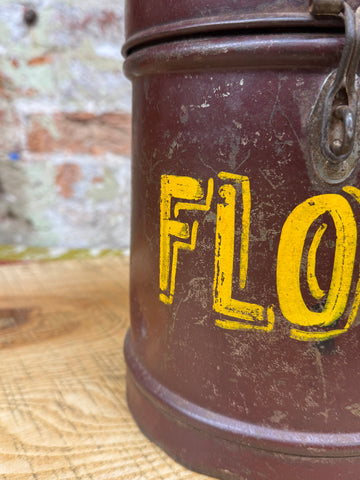 A weathered brown galvanised metal canister with bold yellow letters and vintage latch for flour or dog food storage