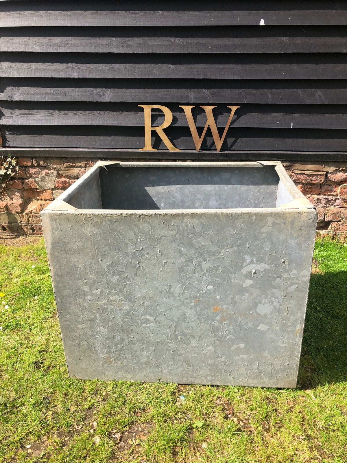 Gray galvanised metal trough planter with textured surface and sharp edges perfect for herb garden or raised bed